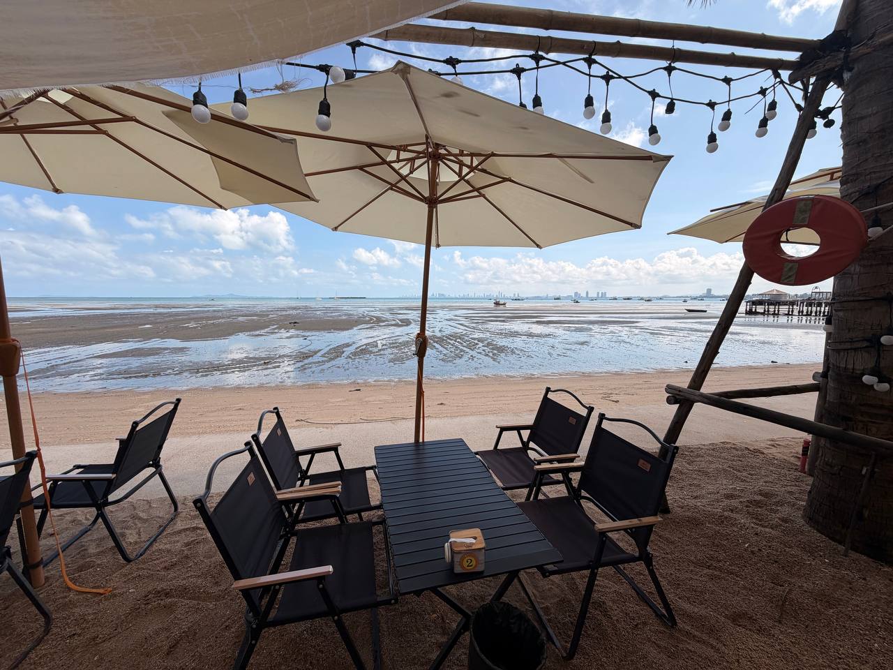 Beach cafe at Bang Saray low tide with Pattaya city skyline on horizon