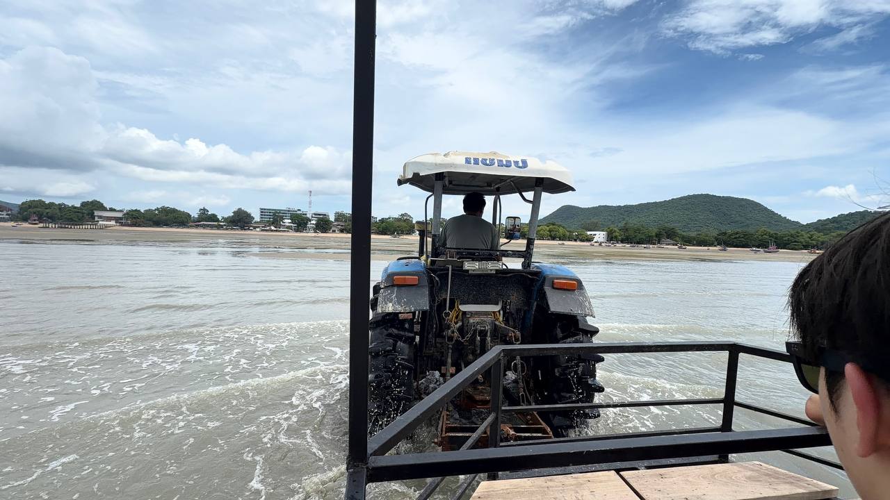 Blue tractor pulling passengers across Bang Saray beach low tide Pattaya