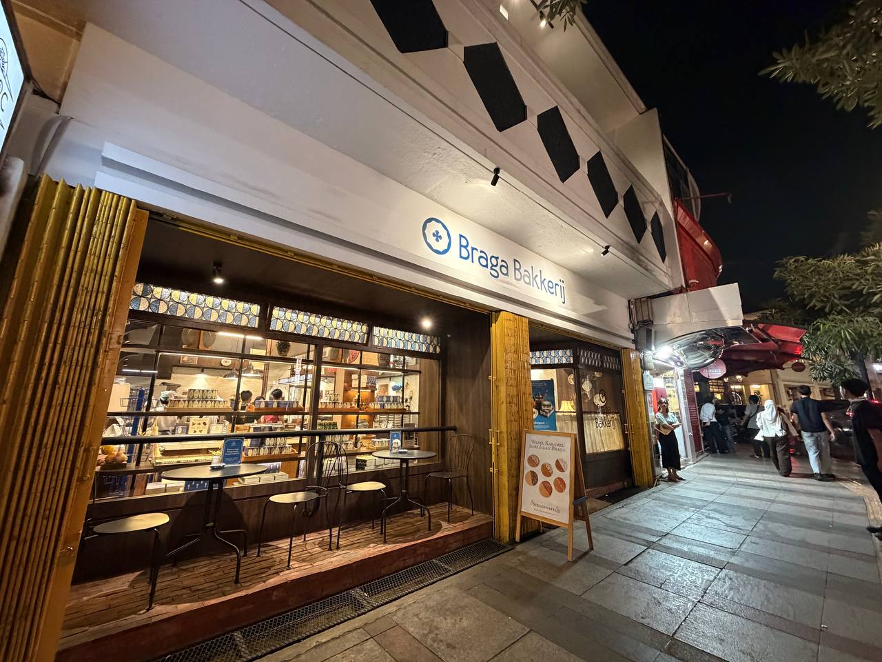 Braga Bakkerij at night — colonial-era Dutch bakery storefront on Jalan Braga, Bandung, with stroopwafel sign and outdoor café tables