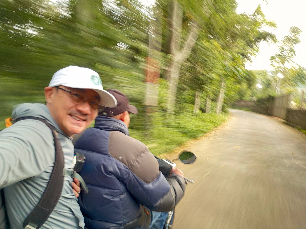 Dawn motorbike ride on the forest road to Tebing Keraton — ojek selfie on a tree-lined mountain road, Bandung highlands