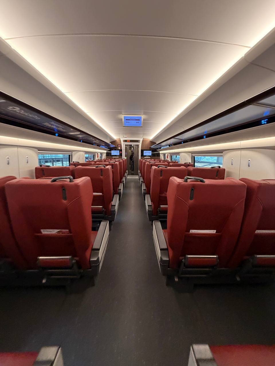 Whoosh high-speed train interior — red leather seats and overhead display screens, Jakarta to Bandung